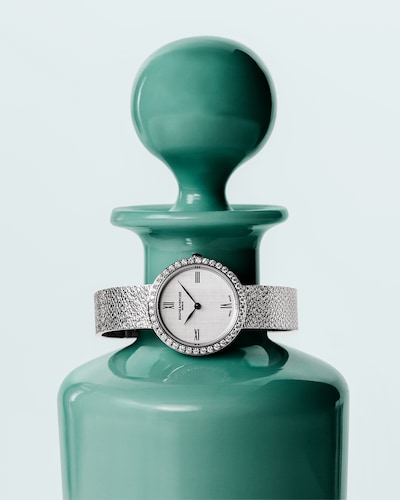 Baume & Mercier Joia collection watch on blue vase. Tap to shop all watches image